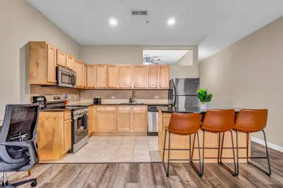 a large kitchen with wooden cabinets and chairs in it at Playhouse Square Suite | Downtown | Parking in Cleveland