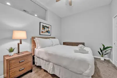 a white bedroom with a bed and a nightstand with a lamp at Central Downtown Condo | Parking & Pool Table in Cleveland