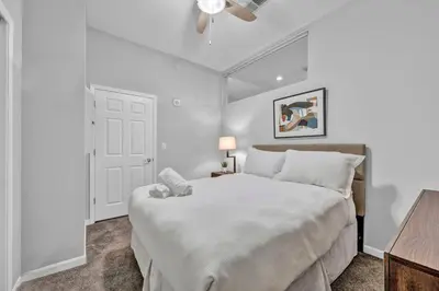 a white bedroom with a large bed and a table at Central Downtown Flat near Attractions and more! in Cleveland