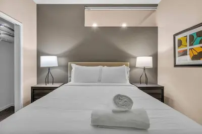 a bedroom with a large white bed with two lamps at Luxe Downtown Condo • Pool Table & Parking in Cleveland