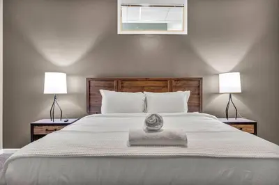 a bedroom with a large white bed with two lamps at Luxe Downtown Condo • Pool Table & Parking in Cleveland