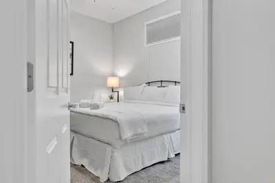 a white bedroom with a bed and a lamp at Theater District Gem • Downtown Hideaway in Cleveland