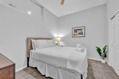 a white bedroom with a large bed and a dresser at Stylish Condo • Walk to Theaters • Parking in Cleveland