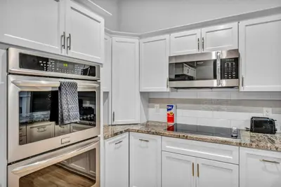 a kitchen with white cabinets and stainless steel appliances at Warm and Cozy Downtown Flat: Paid Parking in Cleveland