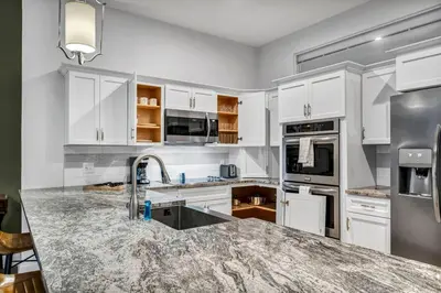 a kitchen with white cabinets and a granite counter top at Stunning Luxury Downtown Condo in Playhouse Square in Cleveland