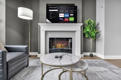 a living room with a fireplace with a tv above it at Super LUX Downtown 1BD Condo | Gym | 24/7 Security in Cleveland