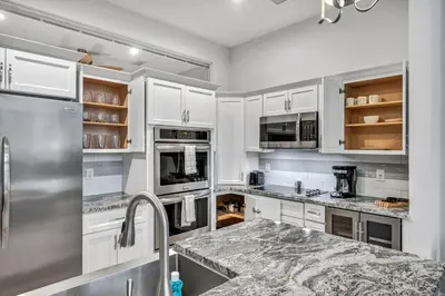 a kitchen with white cabinets and a granite counter top at Luxury Condo Heart of Downtown | 98/100 Walk Score in Cleveland