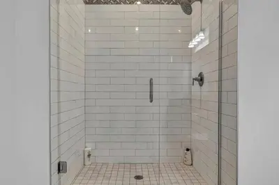 a white tiled shower with a glass door at The Halle Downtown 2BD | Parking/Gym/Security in Cleveland