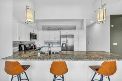 a kitchen with white cabinets and orange chairs at The Halle Downtown 2BD | Parking/Gym/Security in Cleveland