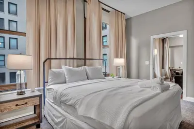 a bedroom with a large white bed and two windows at LUXE Condo Downtown | Security•Gym•Parking in Cleveland