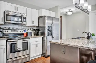 a kitchen with white cabinets and a stainless steel refrigerator at Luxury Loft • Heart of Downtown• Parking/Gym in Cleveland