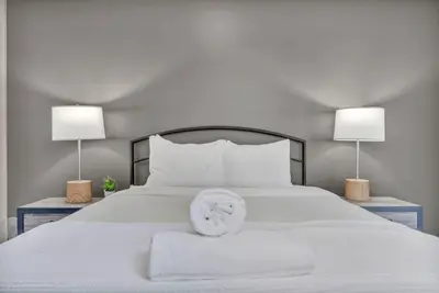 a white bed with two lamps on either side of it at Amazing Downtown Apartment in Incredible Location! in Cleveland