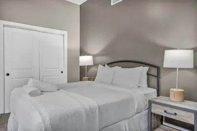 a white bedroom with a large bed and a table at Amazing Downtown Apartment in Incredible Location! in Cleveland