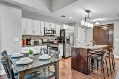 a kitchen with a dining table and a kitchen with white cabinets at Amazing Downtown Apartment in Incredible Location! in Cleveland