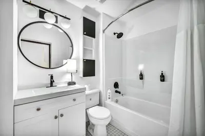 a white bathroom with a sink toilet and a mirror at Elegant Loft in the Heart of Downtown | Gym in Cleveland