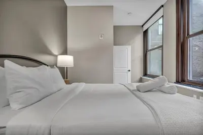 a white bed with white pillows and a window at Central Downtown Loft | Parking•Gym•Security in Cleveland