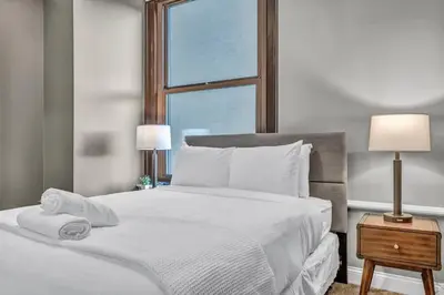 a bedroom with a white bed with two lamps and a window at Modern Loft in the Heart of Cleveland | Gym in Cleveland