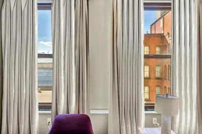 a room with a purple chair in front of a window at Elegant Downtown Apartment | Paid Parking & Gym in Cleveland