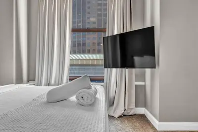 a bedroom with a bed with a flat screen tv at Elegant Downtown Apartment | Paid Parking & Gym in Cleveland