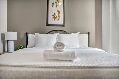 a white bed with a towel on top of it at Elegant Downtown Apartment | Paid Parking & Gym in Cleveland