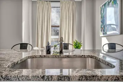 a kitchen with a sink in a marble counter top at Elegant Downtown Apartment | Paid Parking & Gym in Cleveland