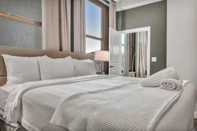a bedroom with a large white bed with a window at Elegant Downtown Loft w/ Parking & Gym in Cleveland
