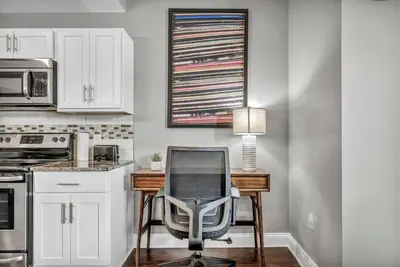 a desk with a chair in a kitchen with white cabinets at Elegant 2BD Condo in the Heart of Downtown • Gym in Cleveland