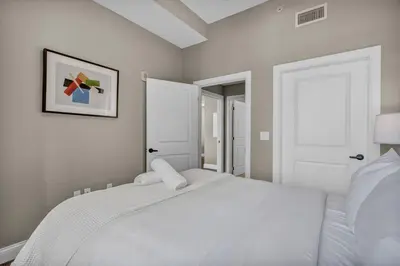 a bedroom with a white bed with a picture on the wall at Luxury 2 BD Condo in the Heart of Downtown • Gym in Cleveland