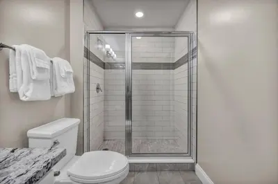 a white bathroom with a shower and a toilet at Elegant Downtown Condo • Fitness Gym Included in Cleveland