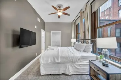 a bedroom with a bed with a ceiling fan and a tv at Elegant Downtown Condo • Fitness Gym Included in Cleveland