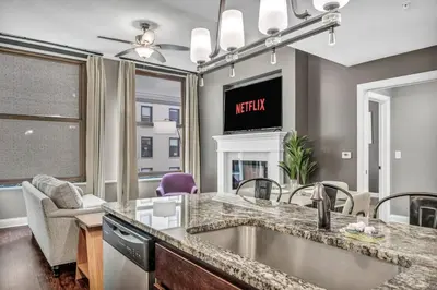 a kitchen with a sink and a living room at Upscale Downtown Loft | Parking • Gym in Cleveland