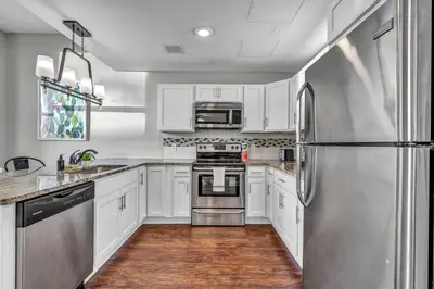 a kitchen with white cabinets and a stainless steel refrigerator at Stunning Downtown Condo with Parking & Gym in Cleveland