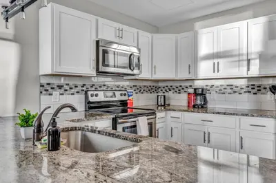 a kitchen with white cabinets and a sink and a microwave at Stunning Downtown Condo with Parking & Gym in Cleveland