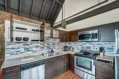 a kitchen with wooden cabinets and stainless steel appliances at Urban Industrial Penthouse | Game Room Pool Table in Cleveland