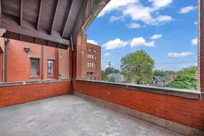 an empty balcony of a brick building with a blue sky at Penthouse Vibes • Fun, Space & City Views in Cleveland