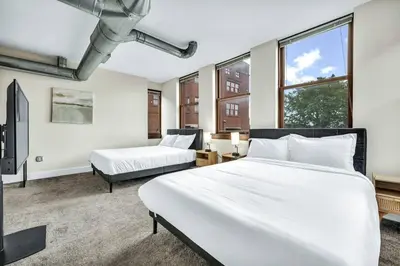 a bedroom with two beds and a tv and windows at Penthouse Vibes • Fun, Space & City Views in Cleveland