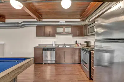 a large kitchen with wooden cabinets and a pool table at Penthouse Vibes • Fun, Space & City Views in Cleveland