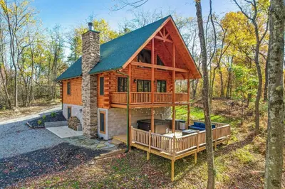 a log cabin in the woods with a wrap around porch at Whiskey Ridge in Logan