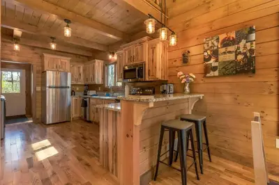 a kitchen with wooden cabinets and a bar with stools at Whiskey Ridge in Logan