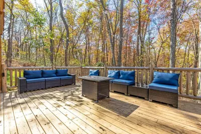 a deck with couches and a table and trees at Whiskey Ridge in Logan