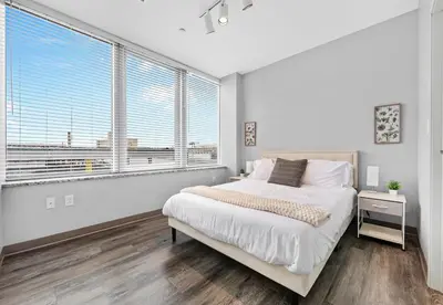 a white bedroom with a bed and large windows at Bright Downtown 1BR l Free Parking l Fast Wi-Fi in Cleveland