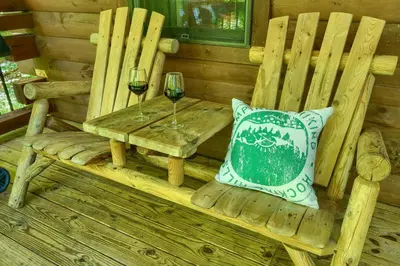 a wooden bench with a table and two glasses of wine at Havenridge in Logan
