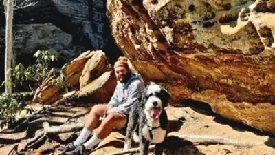 a woman and her dog sitting on a rock at ForgetMeNot in Wellington