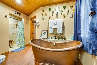 a wooden tub in a bathroom with a sink at Secluded, Waterfront Home with Patio in Craigville!