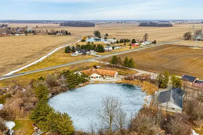 an aerial view of a house and a pond at Secluded, Waterfront Home with Patio in Craigville!