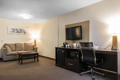 a hotel room with a couch and a desk and a television at MainStay Suites Pittsburgh Airport in Imperial