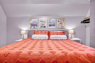 a bedroom with a large orange bed with two lamps at 3rd Floor Retreat Near Cleveland Clinic & Downtown in Shaker Heights