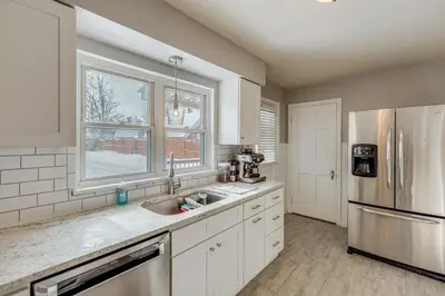 a kitchen with a sink and a refrigerator at Cincy Area Bungalow with Deck and Yard, Pets Welcome! in Covington