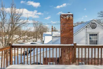 a deck with a brick chimney in the snow at Cincy Area Bungalow with Deck and Yard, Pets Welcome! in Covington