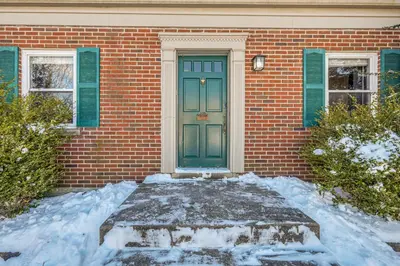 a brick house with a green door in the snow at Cincy Area Bungalow with Deck and Yard, Pets Welcome! in Covington